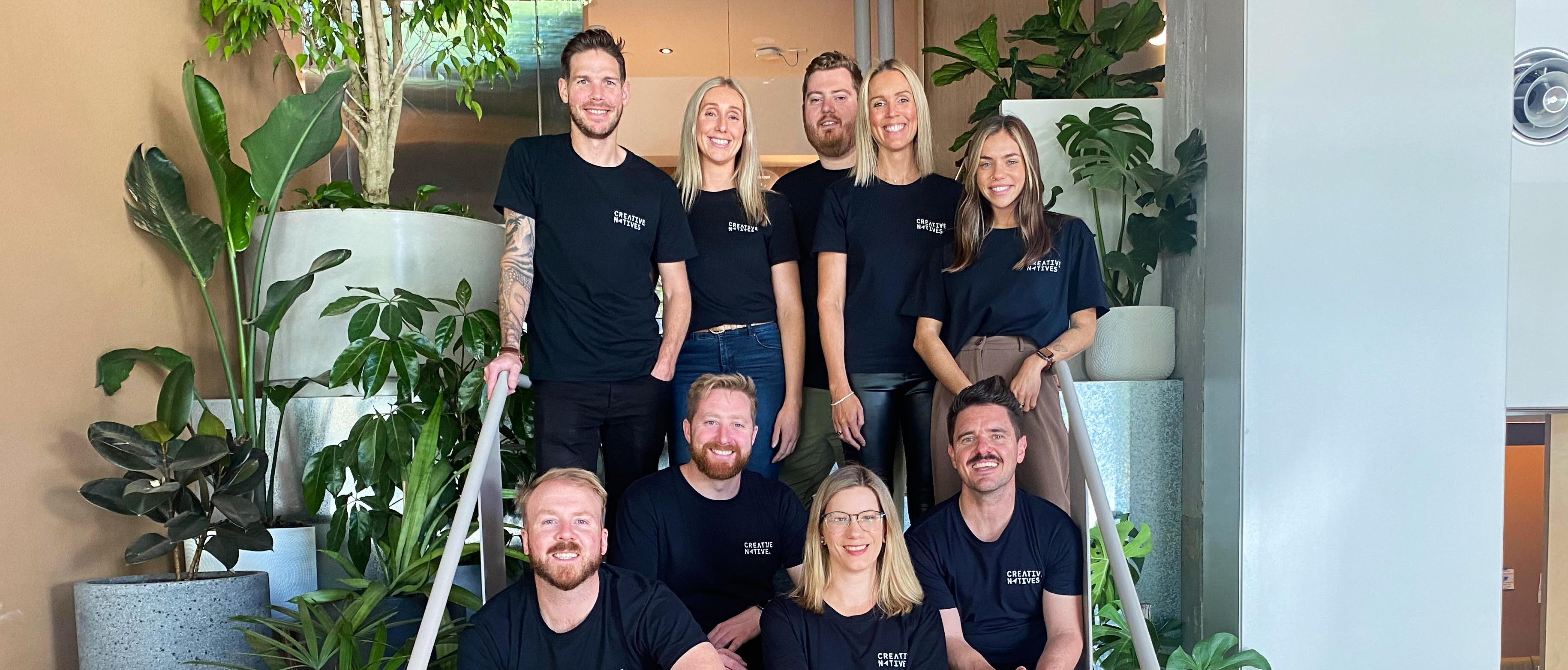 Creative Natives team members standing and sitting on stairs together